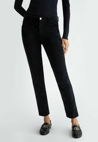 Pantaloni in corduroy neri con una vestibilità slim, forma dritta, tasche frontali e chiusura con bottone. Texture morbida con una leggera lucentezza.
