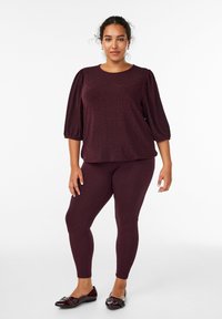 Top borgogna testurizzato con maniche a sbuffo abbinato a leggings coordinati, completato da ballerine borgognone lucide con hardware decorativo.
