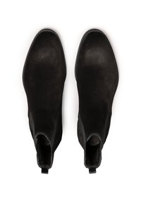 Un par de botas Chelsea de ante negras con paneles laterales de elastano y lengüetas, vistas desde arriba sobre un fondo blanco.