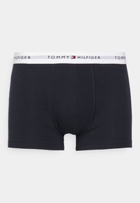 Schwarze Baumwoll-Boxershorts mit einem weißen Bund, auf dem das „TOMMY HILFIGER“-Logo in Schwarz, Rot und Blau abgebildet ist. Glatte Textur, enganliegendes Design.