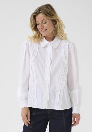 Weiße Bluse mit Rüschendetails entlang der Knopfleiste und Schultern, mit Kragen und langen Ärmeln mit gerafften Manschetten.