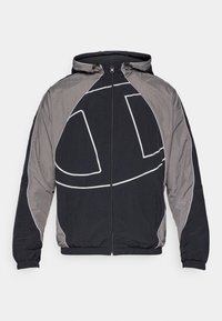 Chaqueta con capucha en negro y gris, con cremallera frontal, que presenta un piping blanco en contraste y un gran diseño de logo en el pecho.