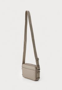 Beige axelremsväska med ett subtilt logomönster, rektangulär form, textpräglad justerbar rem och zip-försedd huvudfack.