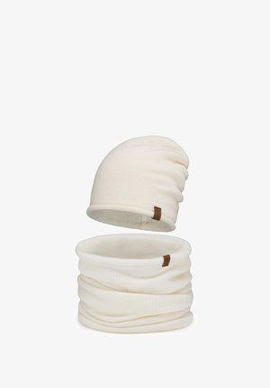 Cremefarbene, gestrickte Mütze und passender Halswärmer. Beide haben eine weiche Textur und tragen ein kleines braunes Markenzeichen.