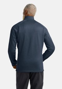 Pullover lungo a maniche lunghe di un blu navy scuro, con colletto alto, maniche a raglan e texture liscia. Design minimalista senza motivi o loghi visibili.
