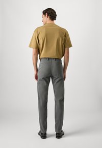 Grijze broeken met een slimfit ontwerp, twee achterzakken, gemaakt van een gladde stof. Gecombineerd met een T-shirt met korte mouwen in mosterdgeel.