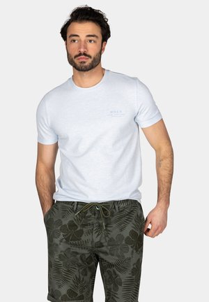 Lichtblauw t-shirt met ronde hals en korte mouwen, voorzien van een subtiele logo-detail, gecombineerd met donkergroene shorts met een bloem patroon.