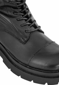 Czarne skórzane botki z zaokrąglonym noskiem, z zapięciem na sznurowadła, kontrastowym przeszyciem i grubą czarną gumową podeszwą z bieżnikiem.