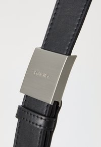 Cintura in pelle nera con una texture liscia e dettagli cuciti, dotata di una fibbia rettangolare in metallo argento incisa con "Calvin Klein".