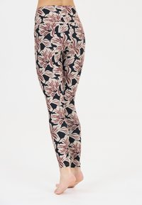 Leggings à motifs avec un design floral en bordeaux et crème, sur un fond noir. Taille élastique et silhouette ajustée.