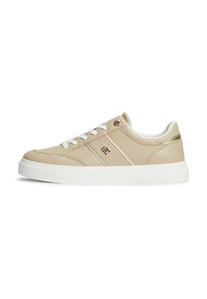 Beige lavtop sneaker med hvide snørebånd, hvid sål, lille metallisk logo på siden og gulddetalje på bagsiden af hælen.