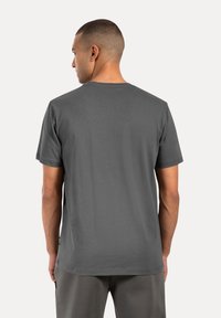 Graues Baumwoll-T-Shirt, kurze Ärmel, Rundhalsausschnitt, glatte Textur, schlichtes Design, mit einem kleinen Etikett am seitlichen Saum.