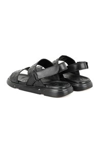 Sandales noires en cuir avec des brides croisées, des détails texturés et une boucle réglable. Semelle en caoutchouc épaisse pour la durabilité et le confort.