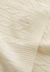 Maglione a trecce color crema con orlo a coste e logo "GANT" ricamato sulla parte del petto.