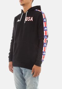 Felpa nera con scritta "USA" in rosso, accentuata da strisce multicolori sulle maniche con loghi. Tessuto morbido e tasca frontale.