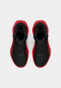 Zwarte en rode sportieve schoenen met een gestructureerde bovenkant, gladde accenten en een instapontwerp. Beschikt over een ronde neus en verhoogde zolen.