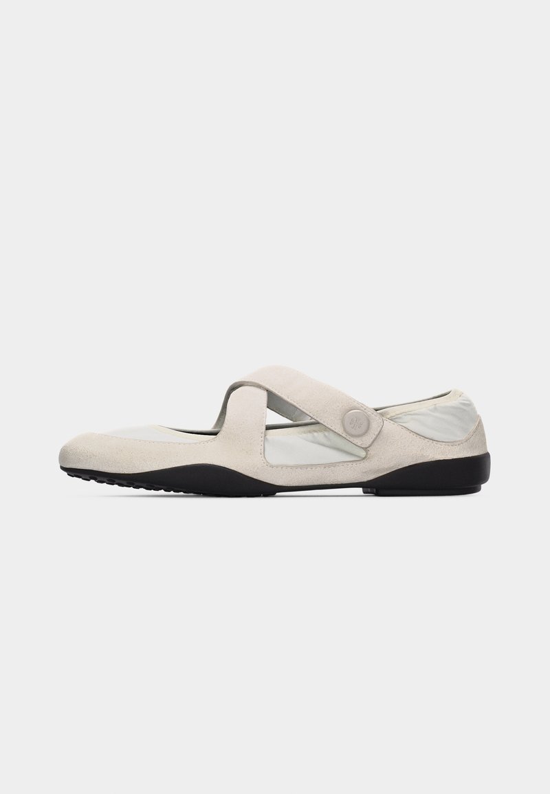 Μπεζ παπούτσι Mary Jane με διασταυρούμενο λουράκι, μαύρη σόλα και απαλή υφασμάτινη επάνω επιφάνεια, σχεδιασμένο για άνετη καθημερινή χρήση.