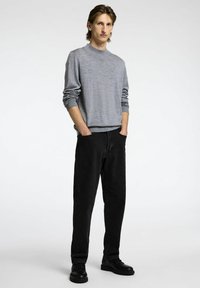 Sivkasta pleteno pulover z visokim krojem, v kombinaciji z ohlapnimi črnimi kavbojkami in črnimi čevlji, z enostavnim dizajnom in sproščeno prileganje.