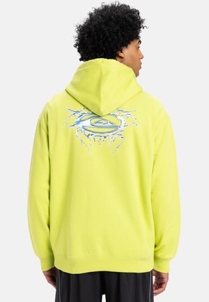 Felpa gialla brillante con cappuccio, caratterizzata da un logo blu stilizzato circondato da crepe sul retro. Tessuto morbido.