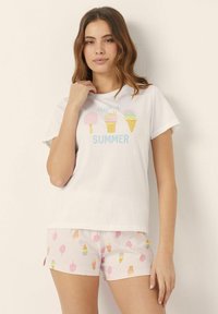 Cotton pajama set featuring a short-sleeve white top with pastel ice cream cone graphics and pink shorts with a matching ice cream motif.
