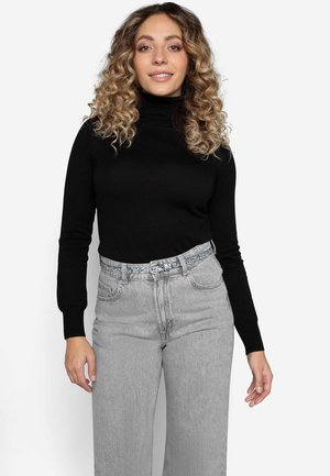 Sort turtleneck sweater med tætsiddende ærmer, parret med højtaljede lysegrå jeans og et mønstret bælte.