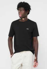 Zwarte katoen T-shirt met korte mouwen, met een klein wit "BOSS" logo op de borst. Draag het met lichte joggingsbroek met koord.