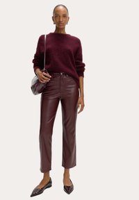 Burgundy stickad tröja, glansiga läderbyxor i burgundy, svarta ballerinas med ögonlappdetaljer och en matchande axelväska.