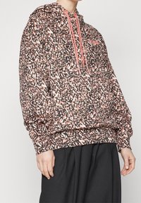 Hoodie w wzórze z mieszanką czarnych, różowych i białych plamek; posiada kaptur ze sznurkiem i luźny krój z elastycznymi mankietami i dołem.