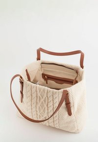 Bolso tote beige tejido con un patrón texturizado, asas de cuero y un bolsillo interior con cremallera. Forrado con tela en un tono neutral.