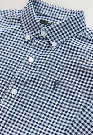 Chemise à boutons en motif vichy bleu marine et blanc, en coton. Dotée d'un col, de boutons blancs et d'un logo brodé discret.