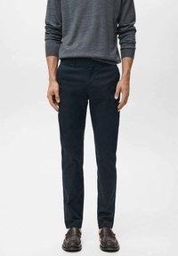 Mörkblå herrchinos, tillverkade av mjukt tyg, med rak skärning, framfickor och en enkel knappstängning.