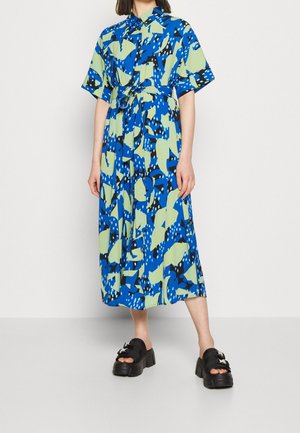Blue and green patterned shirt dress with short sleeves, a waist tie, and a mid-length skirt. Features abstract shapes and a relaxed fit.
