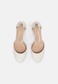 Vita läderslingback-skor med rund tå, elastiskt band och slät yta. Ljusbruna innersulor. Minimalistisk design.