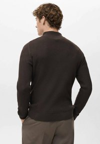 Jersey marrón de punto canalé con cuello alto, puños ajustados y cinturilla. Tejido texturizado, detalles visibles de costura en la parte trasera.