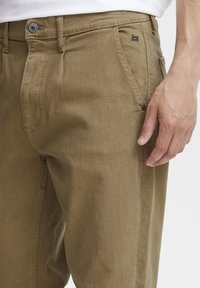 Pantaloni khaki realizzati in tessuto morbido con un design a gamba dritta. Presentano una chiusura frontale a bottone e tasche laterali per una maggiore funzionalità.
