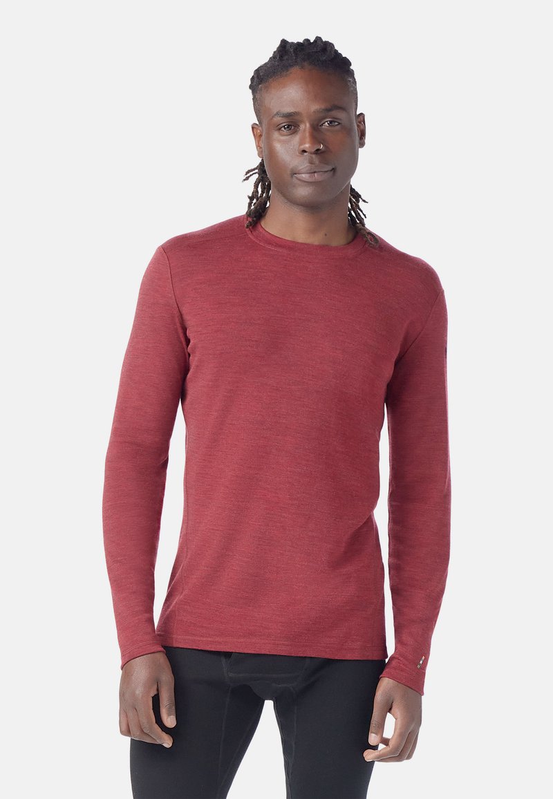 Camicia a maniche lunghe di un rosso intenso, realizzata in tessuto testurizzato. Presenta un collo rotondo e una silhouette aderente con dettagli minimi e cuciture sottili.
