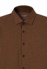 Braune, geknöpfte Hemd aus strukturiertem Stoff; mit einem spitzen Kragen und sechs schwarzen Knöpfen an der Vorderseite. Größe-Etikett innen sichtbar.