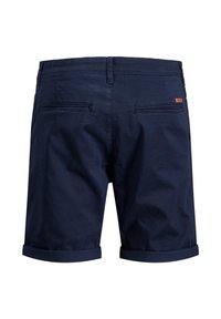 Shorts en coton bleu marine avec une texture lisse, munis de revers roulés, deux poches arrière et une petite étiquette logo sur la poche arrière droite.