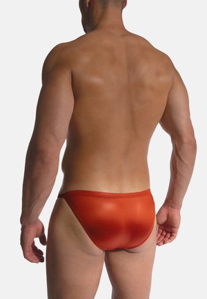 Rote Badehose aus einem glänzenden, glatten Stoff. Verfügt über einen niedrigen Bund und minimale Bedeckung, mit einem einfachen Taillenbund-Design.