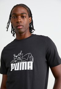 Sort bomulds T-shirt med et hvidt grafik af en panter og "PUMA" logoet nedenfor. Rund hals og korte ærmer.