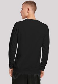 Mustast pehmest kangast crewneck-sviitrist, millel on pikad varrukad ja lõdva lõige. Seljal on minimaalne detailitus ja pole graafikat.