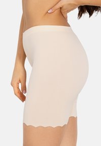 Nude naadloze shorts met een scalloped zoom, gemaakt van glad, elastisch materiaal. Ontworpen voor comfort en discreet laagjes dragen.