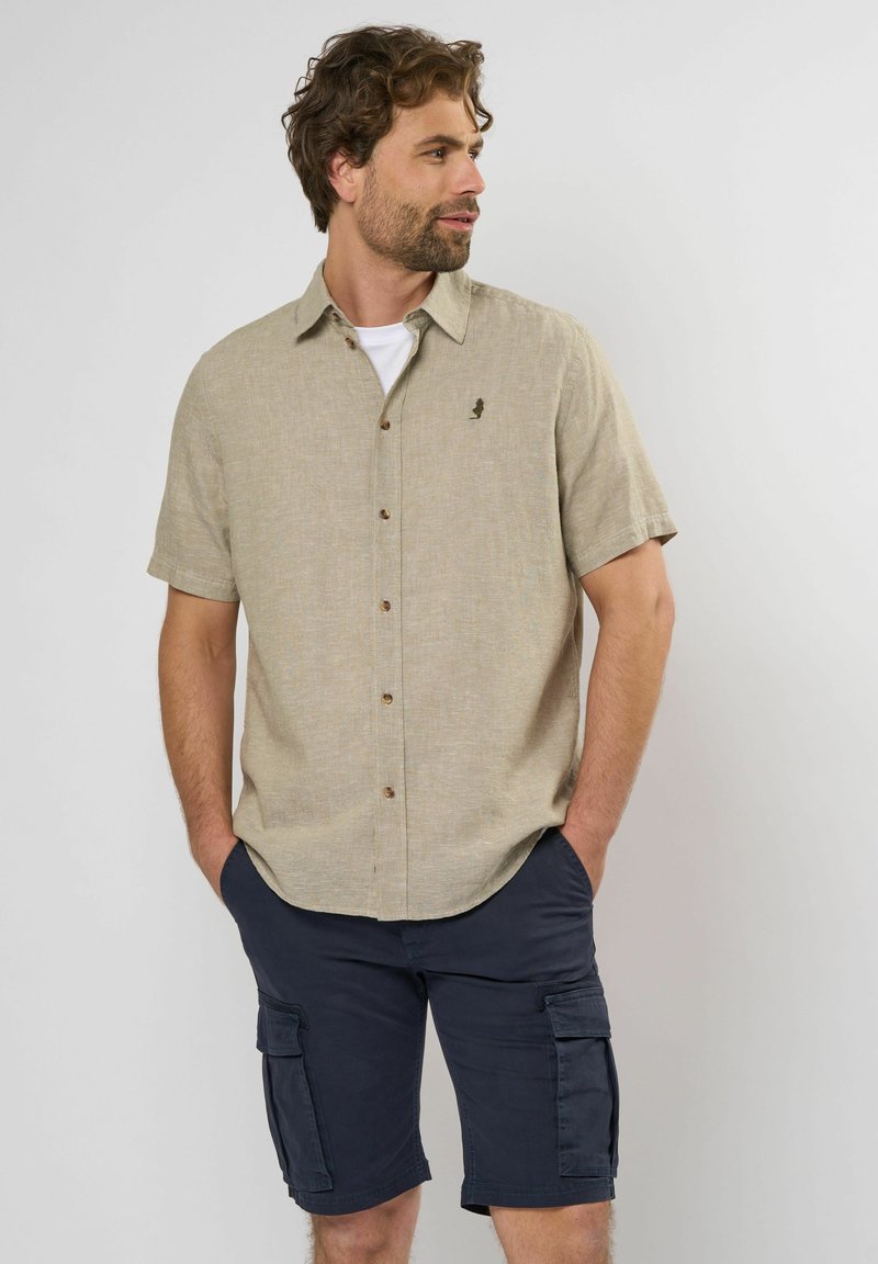 Lys brun kortærmet skjorte med krave, tekstureret stof og brune knapper. Parret med marineblå cargo shorts med sidelommer.