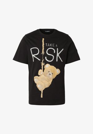 Fekete póló, amelyen egy mackó kötelet mászik, beépítve a „Take a Risk” feliratba fehér betűkkel.