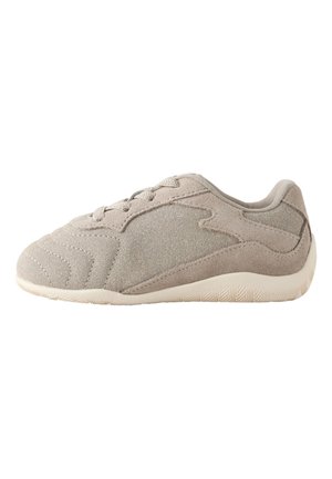 Jasnobeżowy zamszowy sneaker z wiązaniem z przodu, szczegółowym przeszyciem i białą teksturowaną podeszwą, widoczny od zewnętrznej strony.