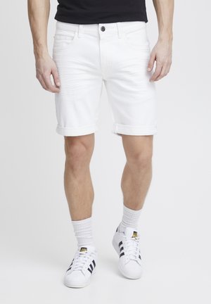 Vita denimshorts med uppvikta fållar, lätta slitningar och framfickor. Bärs med vita sneakers och vita strumpor.