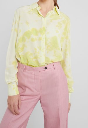 Blouse tie-dye jaune clair et vert avec col, manches longues et fermeture à boutons, assortie à un pantalon rose sur mesure.