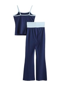 Marineblaues Tanktop mit dünnen Trägern und hellblauer Einfassung, kombiniert mit passenden marineblauen Schlaghosen mit hellblauem Bund.