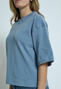 Blå bomulds T-shirt med afslappet pasform, korte ærmer og rund halsudskæring. Har en glat tekstur og sidesømmer for struktur.