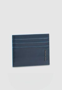 Donkeren blauwe leren kaarthouder met een gladde textuur, voorzien van vier kaartvakken en een metalen logo-accent. Eenvoudig, slank design.